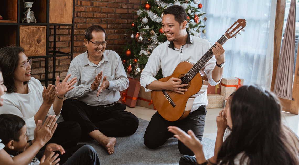 Family playing the guitar and singing under the Christmas tree