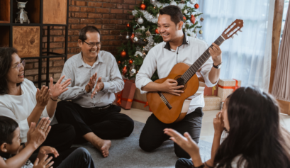 Family playing the guitar and singing under the Christmas tree