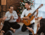 Family playing the guitar and singing under the Christmas tree