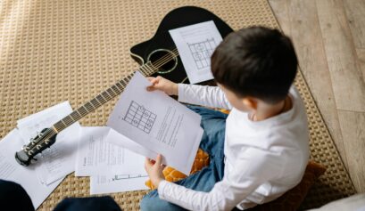 kid learning to read musical notes on an acoustic guitar, practicing sheet music for easy guitar lessons.