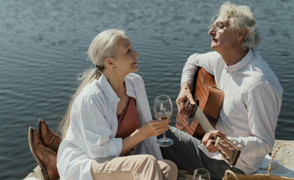 Couple sitting on the beach, playing love songs on guitar