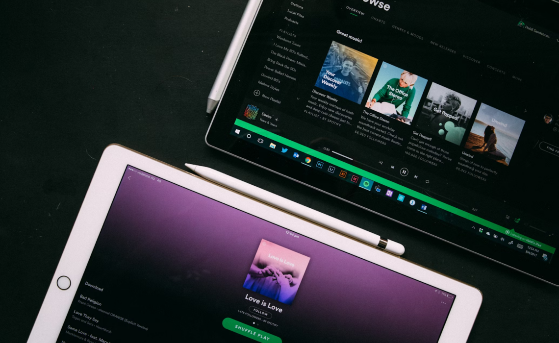 Two tablets displaying Spotify, one showing a playlist and the other the browse section.